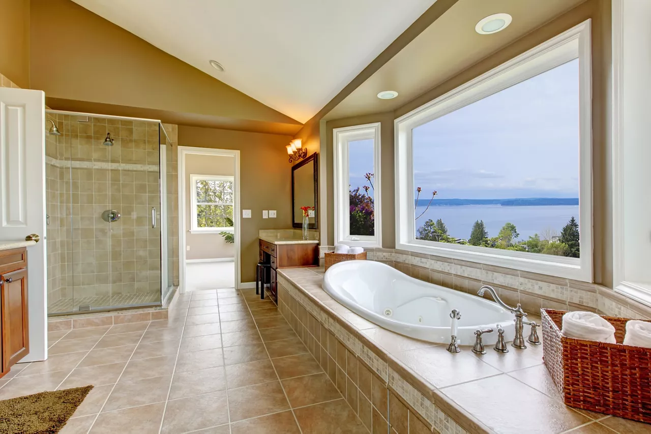 Large bath tun with water view and luxury bathroom interior in beige colors.