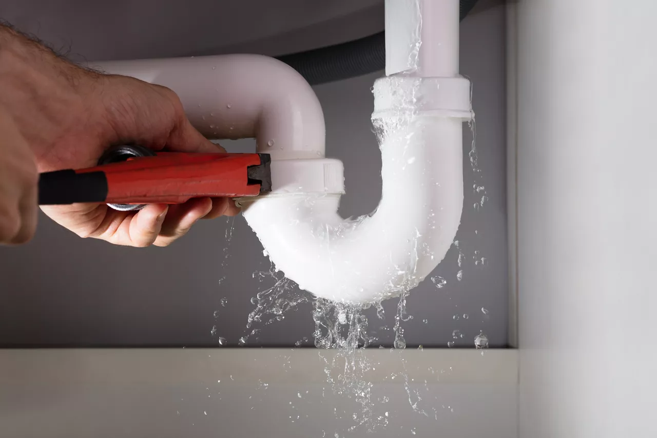 Close-up Of Male Plumber Fixing White Sink Pipe With Adjustable Wrench