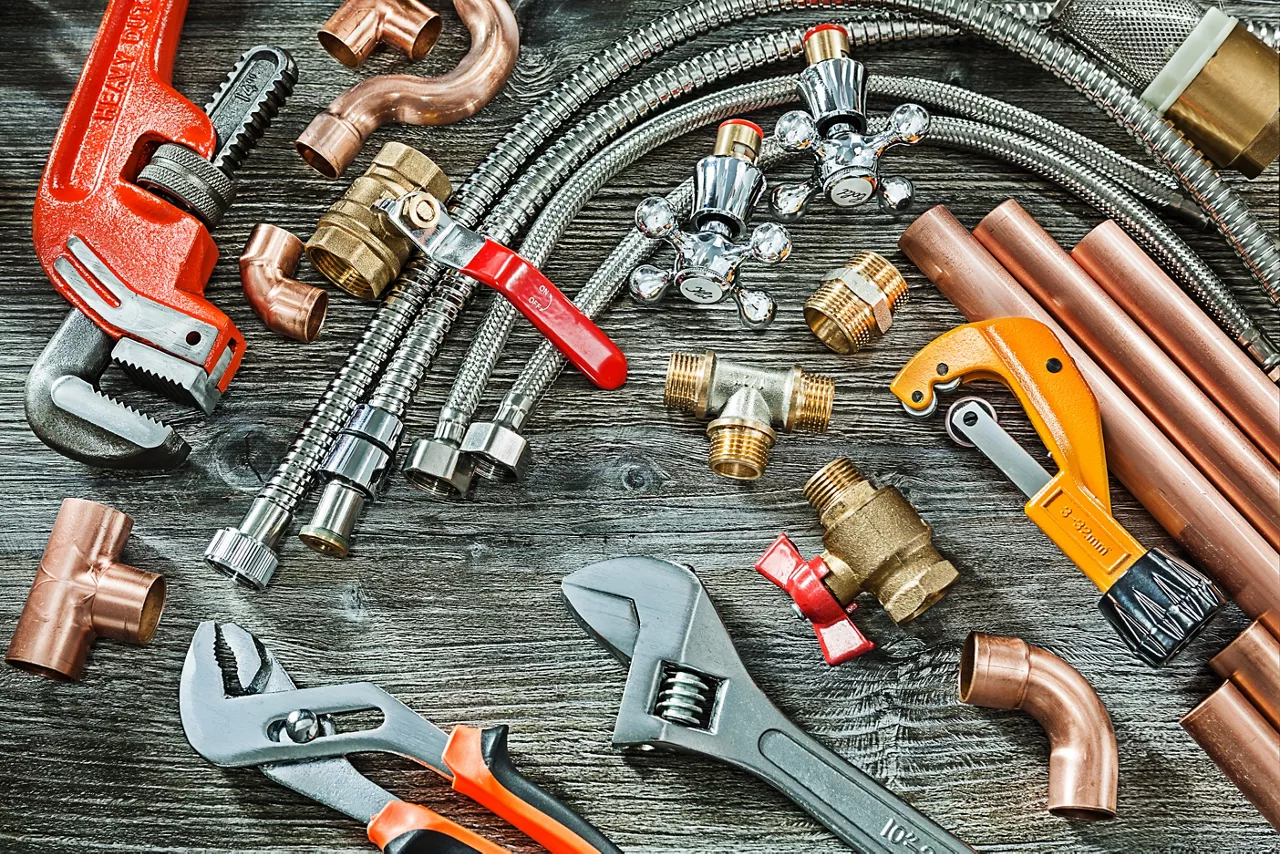 plumbing concept big set of piping accessories monkey and plumb adjustable wrenches copper brass fittings pipe cutter on vintage wood background