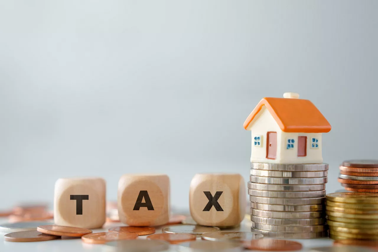 House model on growth of stack of coins and wooden blocks text TAX. Background for prepare budget for reduce property tax, Land transfer taxation and Investment income tax from asset.