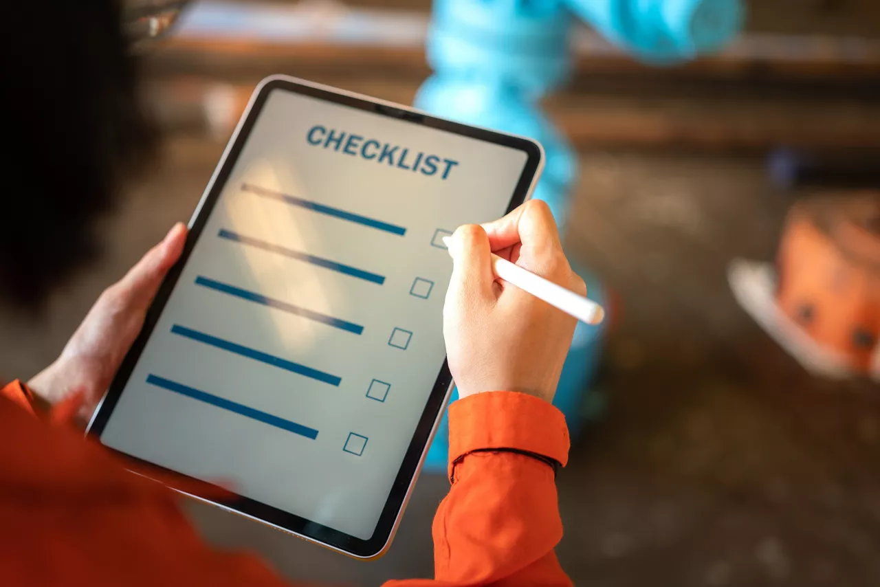 Action of a engineer is using digital pen to checking checklist on tablet with background of factory workplace. Industrial and technology working concept. Close-up and selective focus at hand's part.