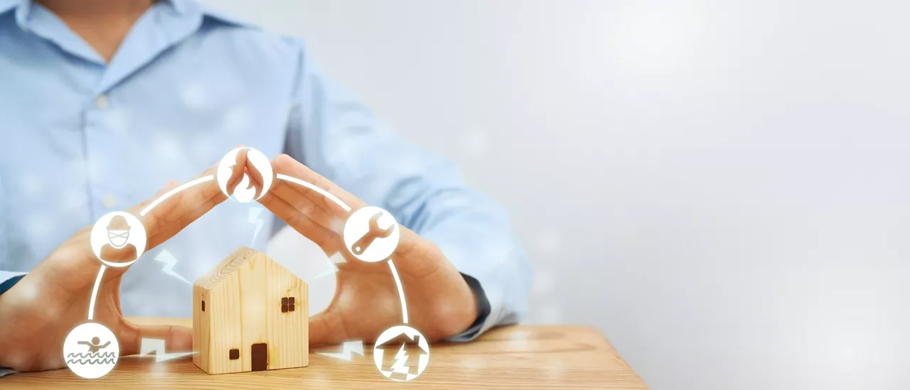 Female hands showing gestures protect a model wooden house. Residential care ideas. Concept of home protection and insurance against natural disasters and theft.