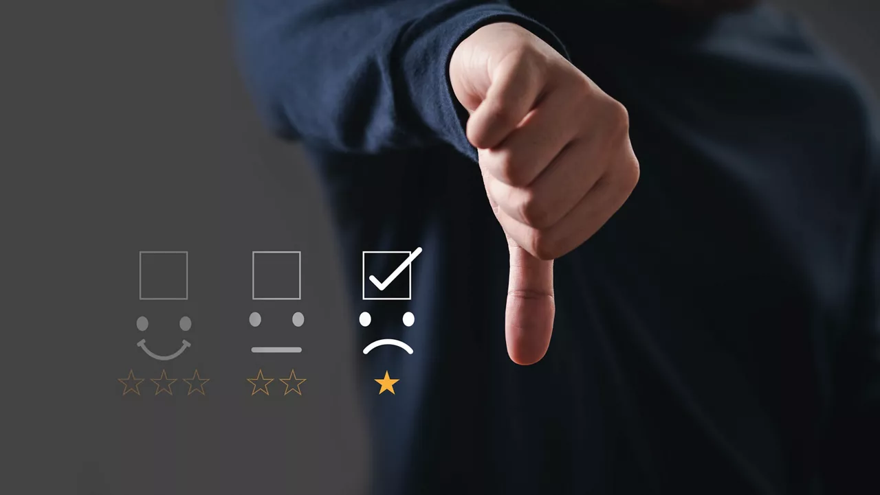 Hand giving thumbs down next to rating icons with a low rating selected, symbolizing negative feedback or dissatisfaction.