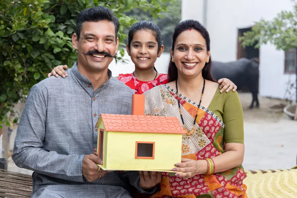 Indian family holding model house at village.