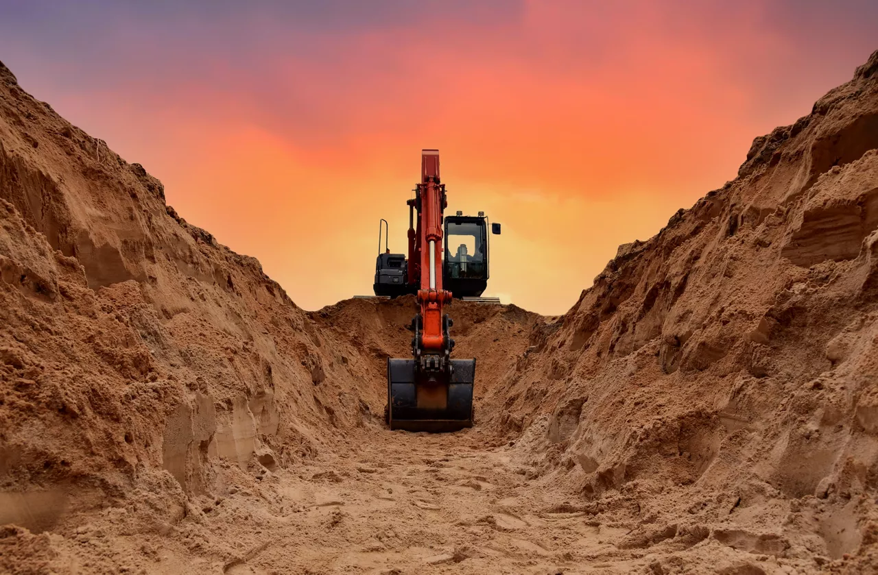 Excavator dig trench on sunset background. Backgoe on earthwork. Construction natural gas pipeline. Construction the sewage and drainage.  Laying sewer pipes at construction site. Open pit mining.