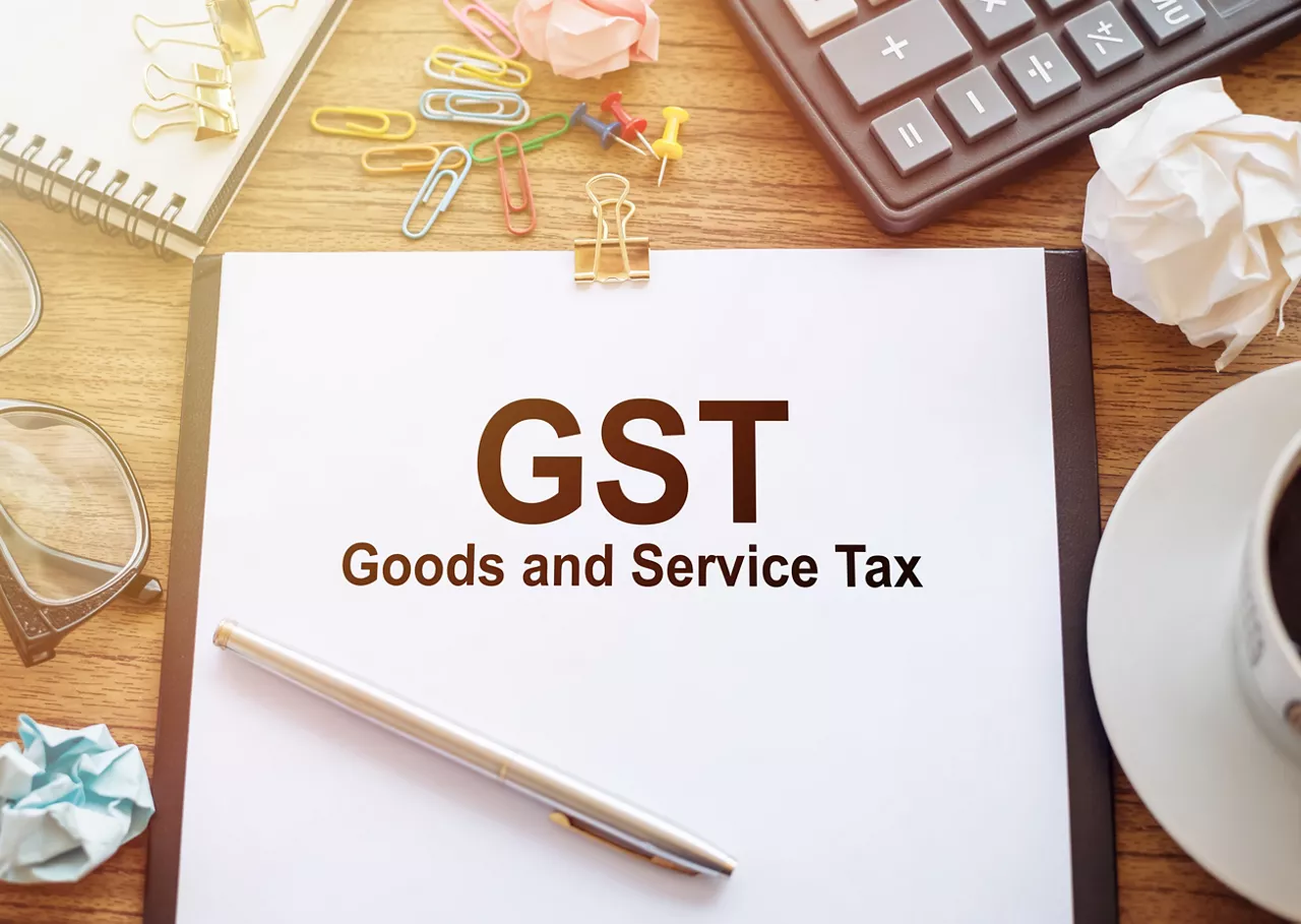 White Paper With GST Goods and Service Tax Written on Wooden Desk