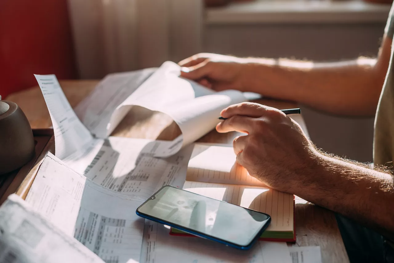 Close-up of men's hands with a calculator and utility bills. The concept of rising prices for heating, gas, and electricity. Lots of utility bills and hands with a calculator and a notebook