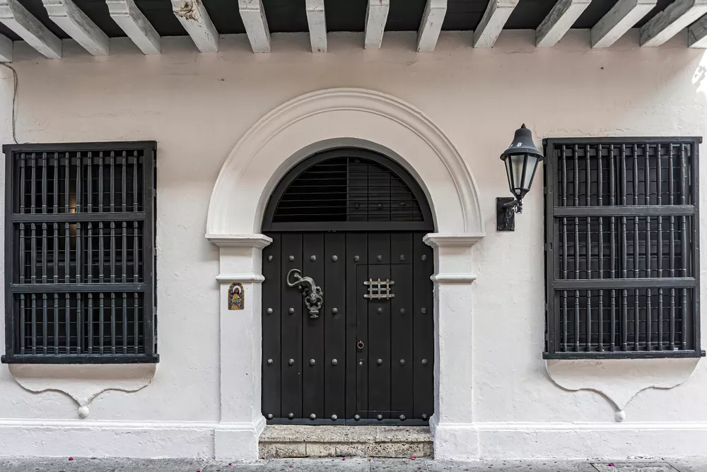 Facade of a colonial style house with old wooden door with a lamp beside