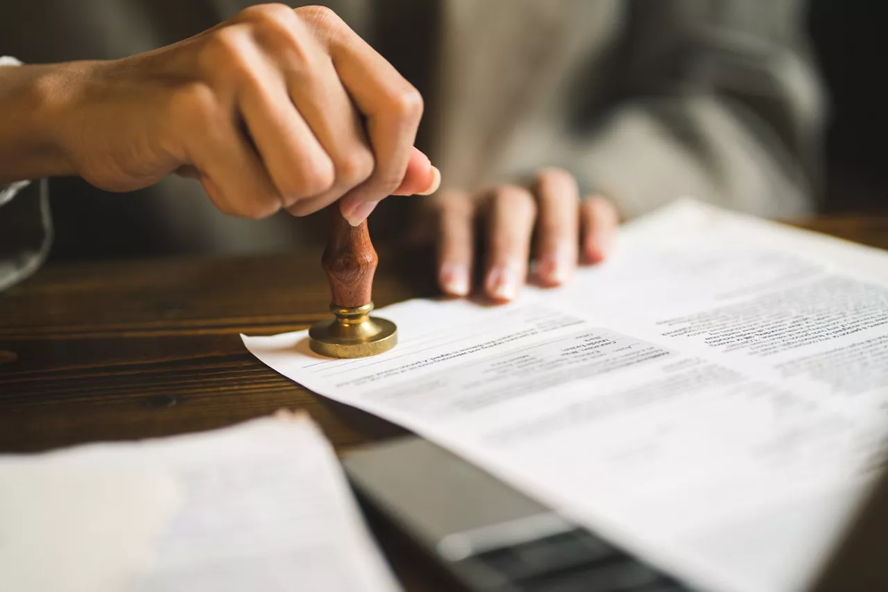 Close-up of person stamping documents to approve agreements,