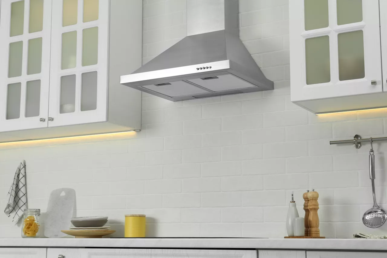 Elegant kitchen interior with modern range hood over cooktop and stylish furniture