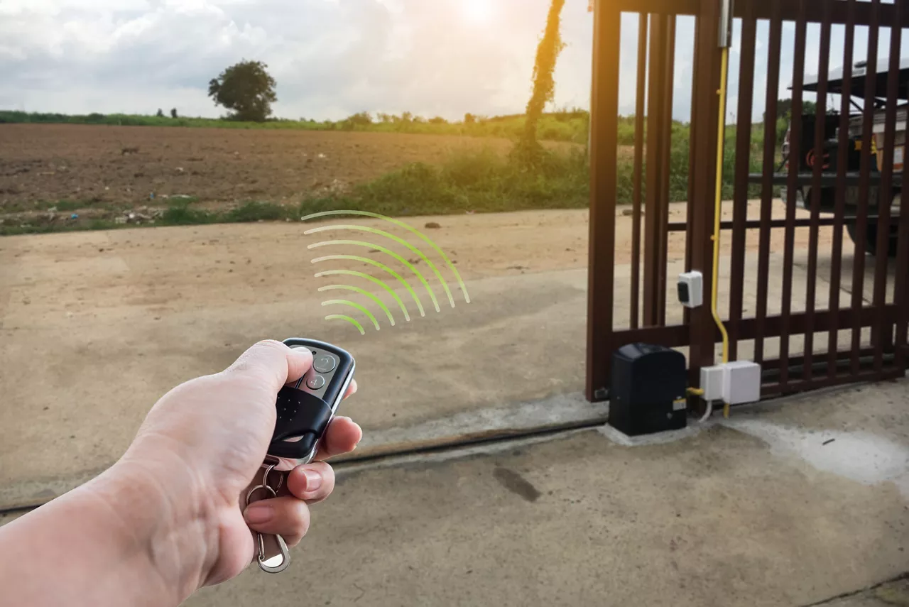 Signal of remote control when person open automatic gate at house for home security system with sunlight rays