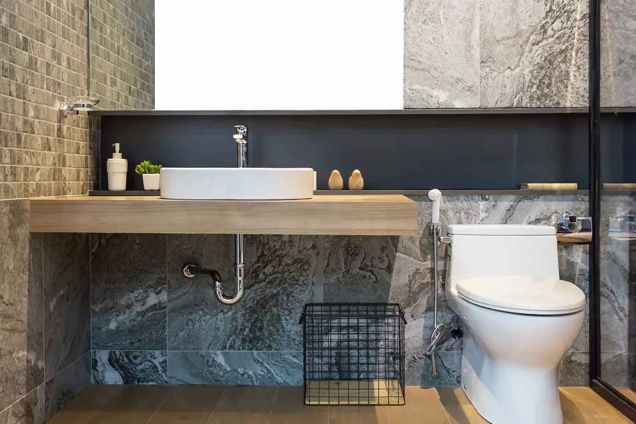 Modern spacious bathroom with bright tiles with toilet and sink. Side view