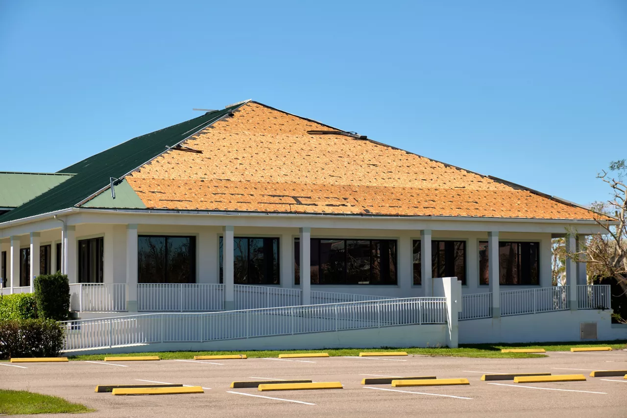 Wind damaged house roof with missing asphalt shingles after hurricane Ian in Florida. Repair of home rooftop concept