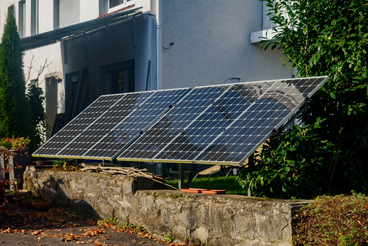 Solar panels, mounted on the ground in the yard of residential home. Solar panels positioned on metal frame in residential garden as eco-friendly, energy-efficient solution for harnessing solar power.