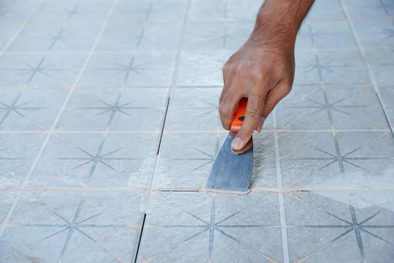 Tiler laying the ceramic tile on the floor. Grouting ceramic tiles. Professional worker makes renovation. Construction. Hands of the tiler. Home renovation and building new house