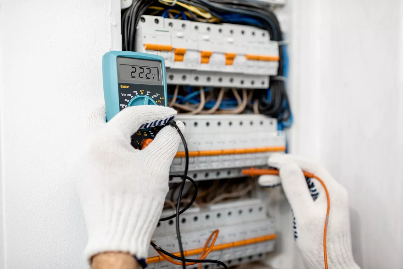 Electrician installing or repairing apartment electrical panel, close-up view