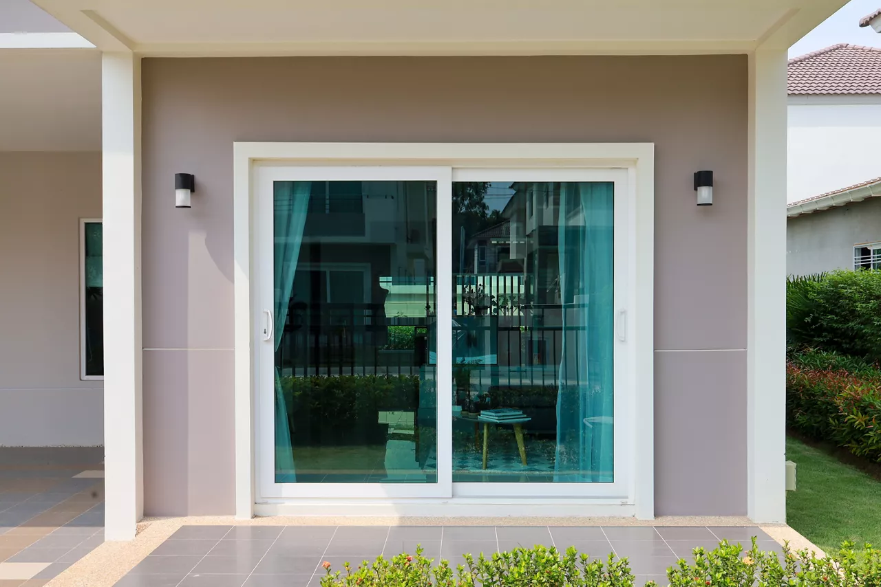 Green clear glass attached to the sliding door and wall of the house.