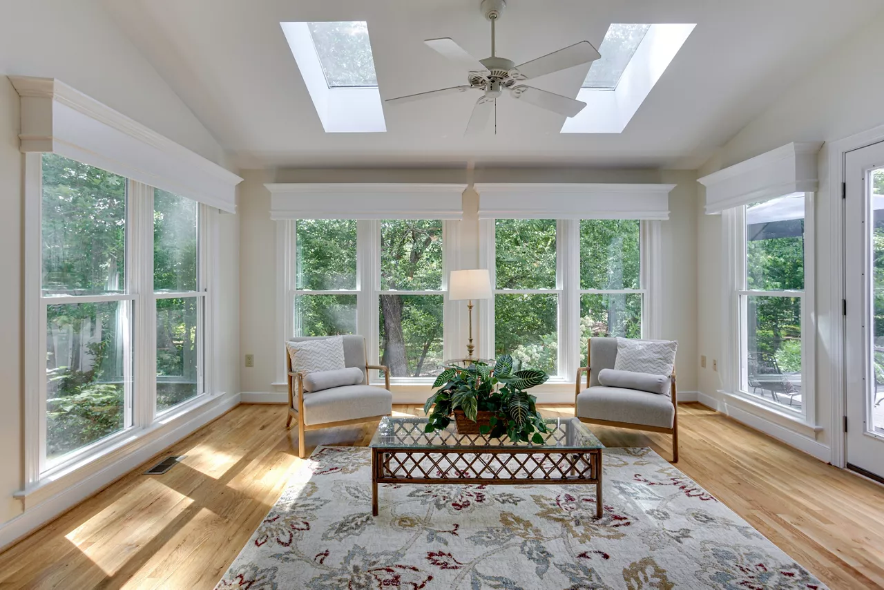 Bright Sunroom With Skylights, Armchairs, And View Of Lush Green Garden