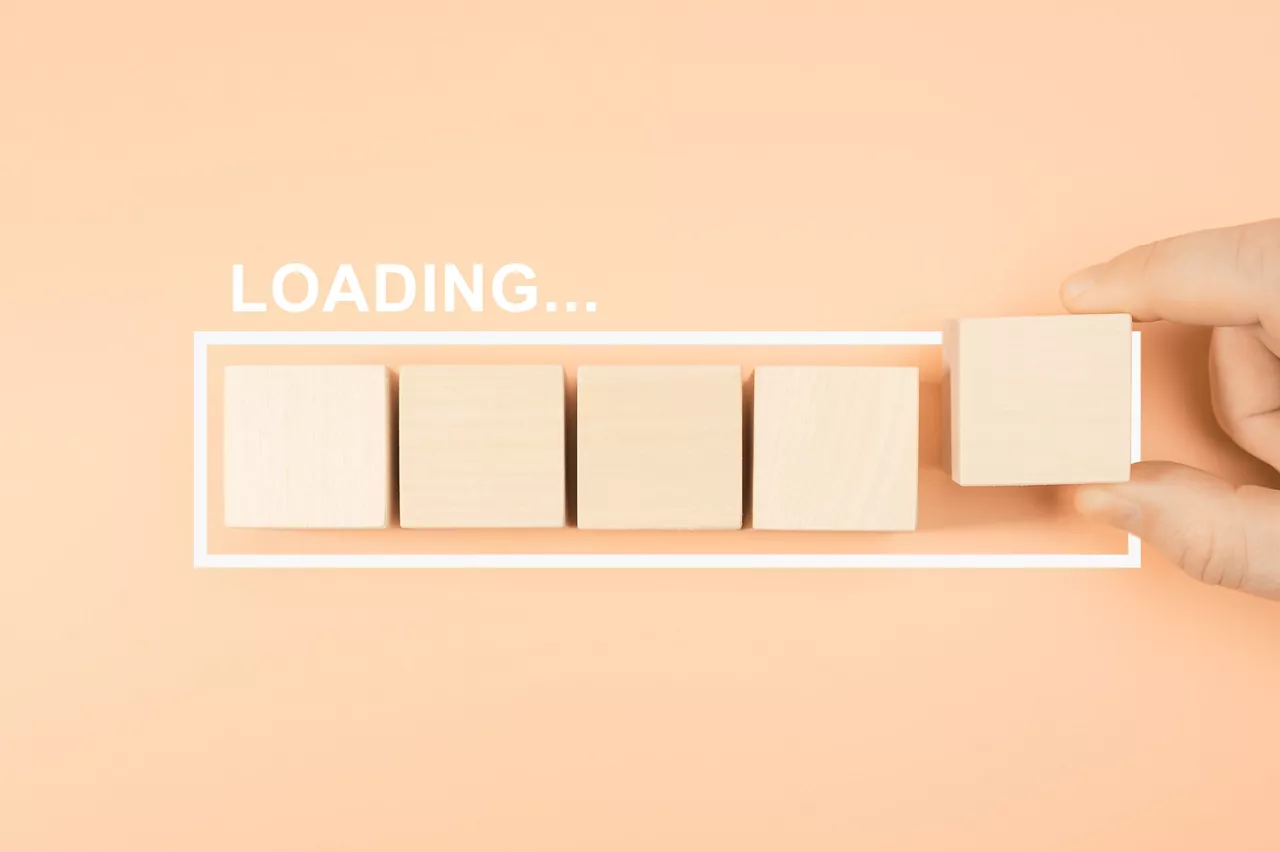 Loading bar with wood cube on pastel background. Wooden blocks with the word LOADING in loading bar progress. Concept loading. Hand putting wooden cube block shape on load