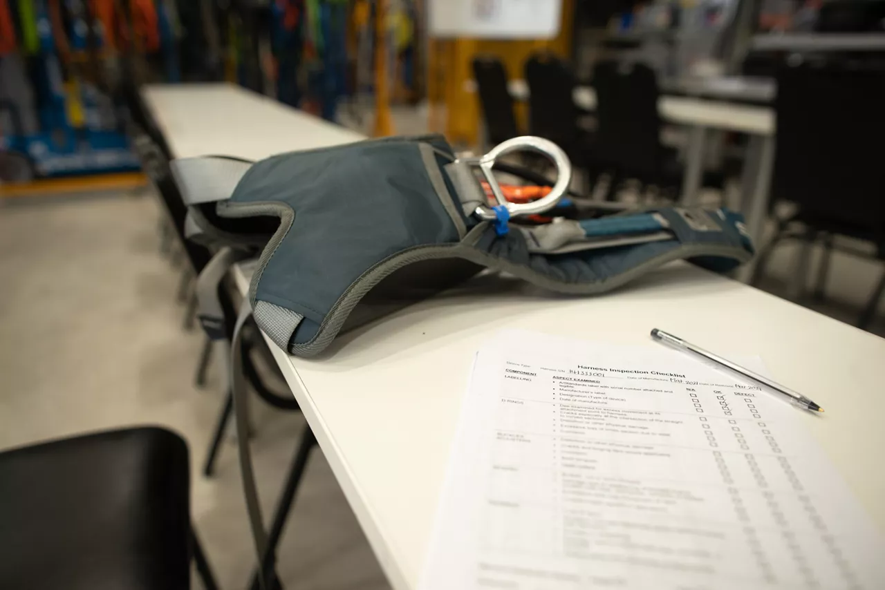 Harness inspection checklist paper placing on the table, defocused harness, shock absorber lanyards fall arrest fall protection safety assessment prior to work approval sign off of each task 