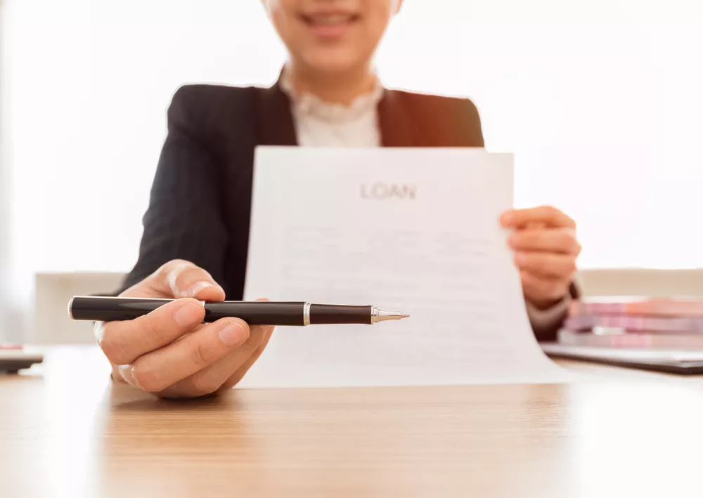 The banker handed the pen for signing in loan document and agreement. Loan concept.
