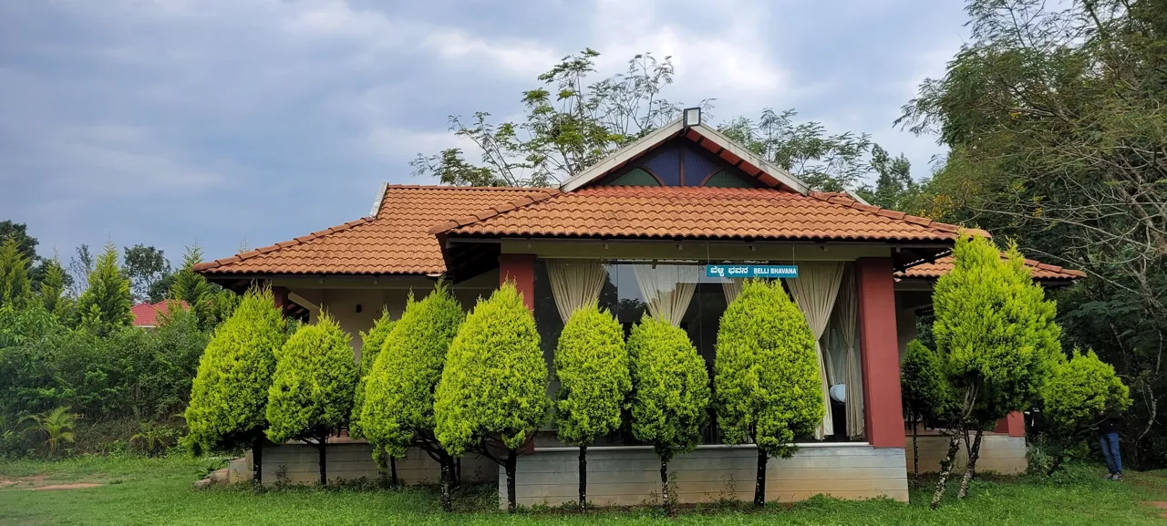 Chikkamagaluru Farm country house in the field with fence. Countryside of India. Rural Farmhouse with trees on a sunny day in a summer. Beautiful house entrance with a garden and green lawn.