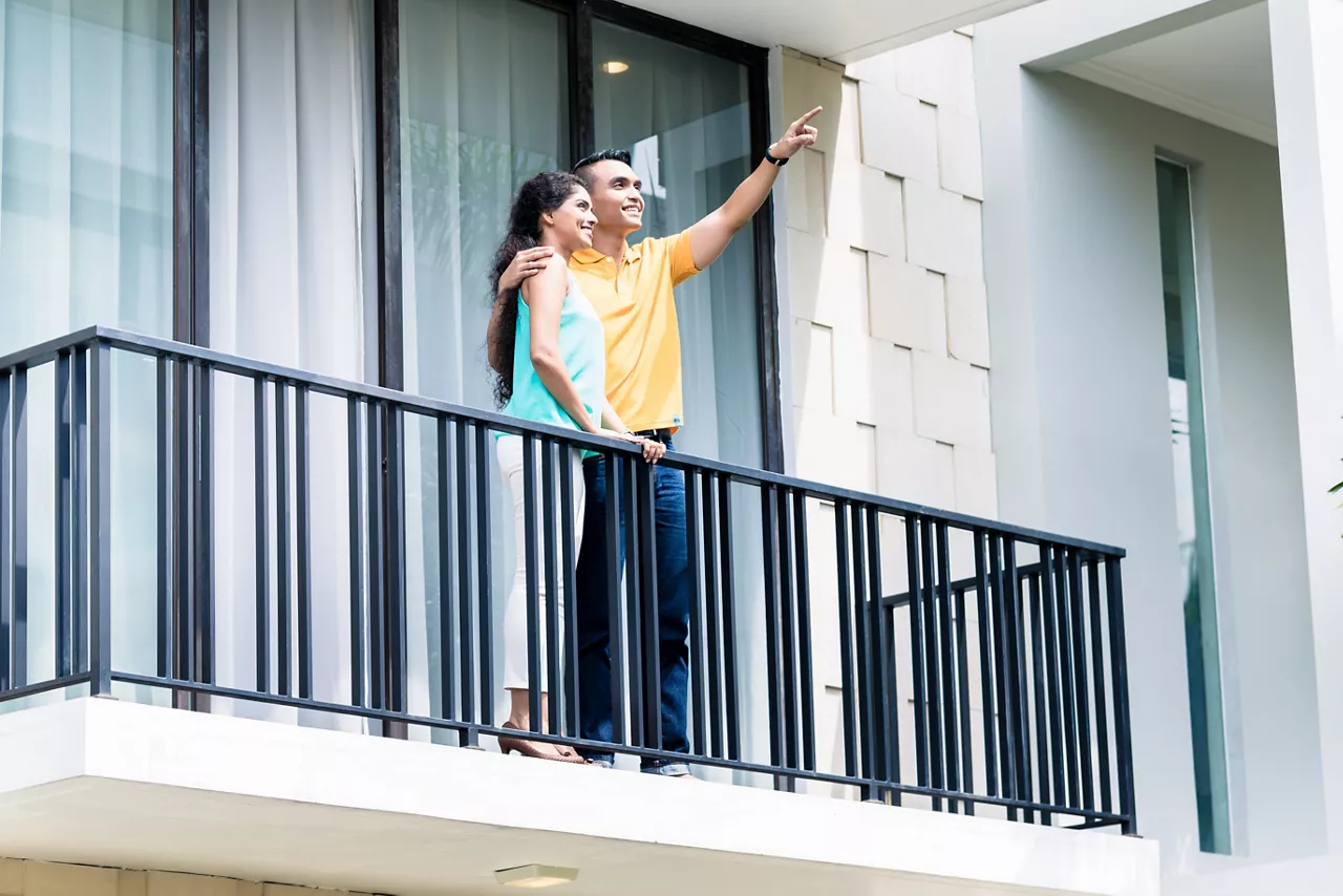 Indian woman and man standing on balcony of their new home