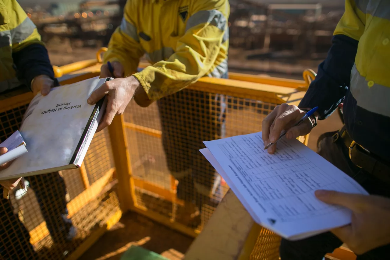 Trained supervisor safety auditor competent reviewing document issued sign approvals of working at height permit JSA risk assessment on site prior to performing high risk work mining construction site
