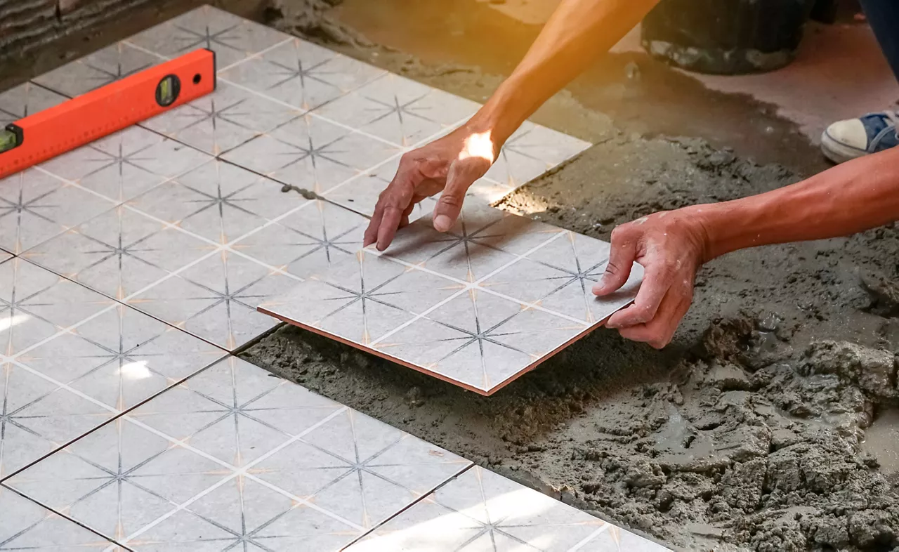 Floor tiles installation. Ceramic tiles and tools for tiler. Home improvement, renovation - ceramic tile floor adhesive, trowel with mortar, level.