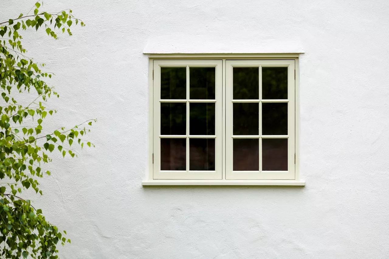 UK house exterior with wooden casement window and white wall rendering