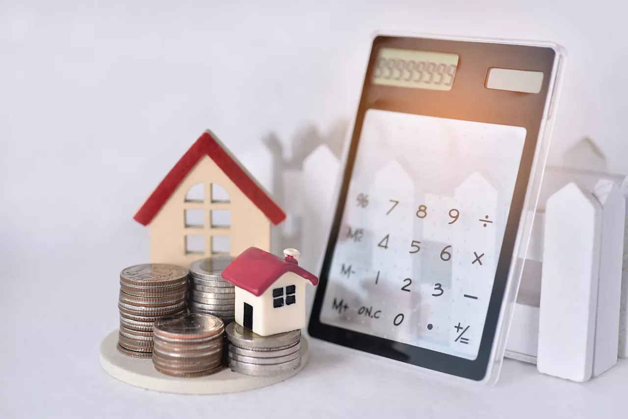 Stacking coins with the two red roof house and the calculator lean against the sunrise for calculate the home payment interest of  house loan monthly installment or an equated monthly installment 