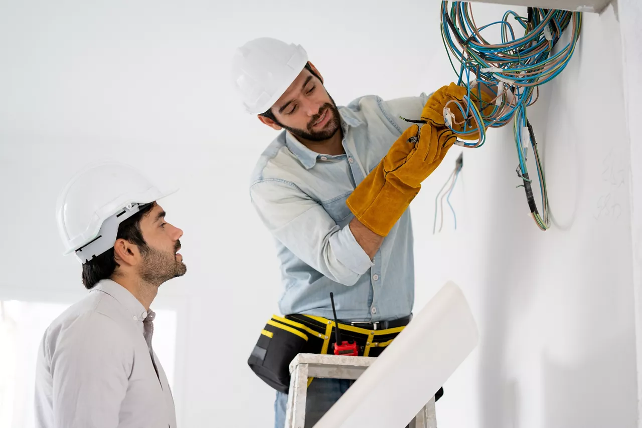 Electrician mounting wiring for electric sockets on the construction site of a new house,Construction concept.