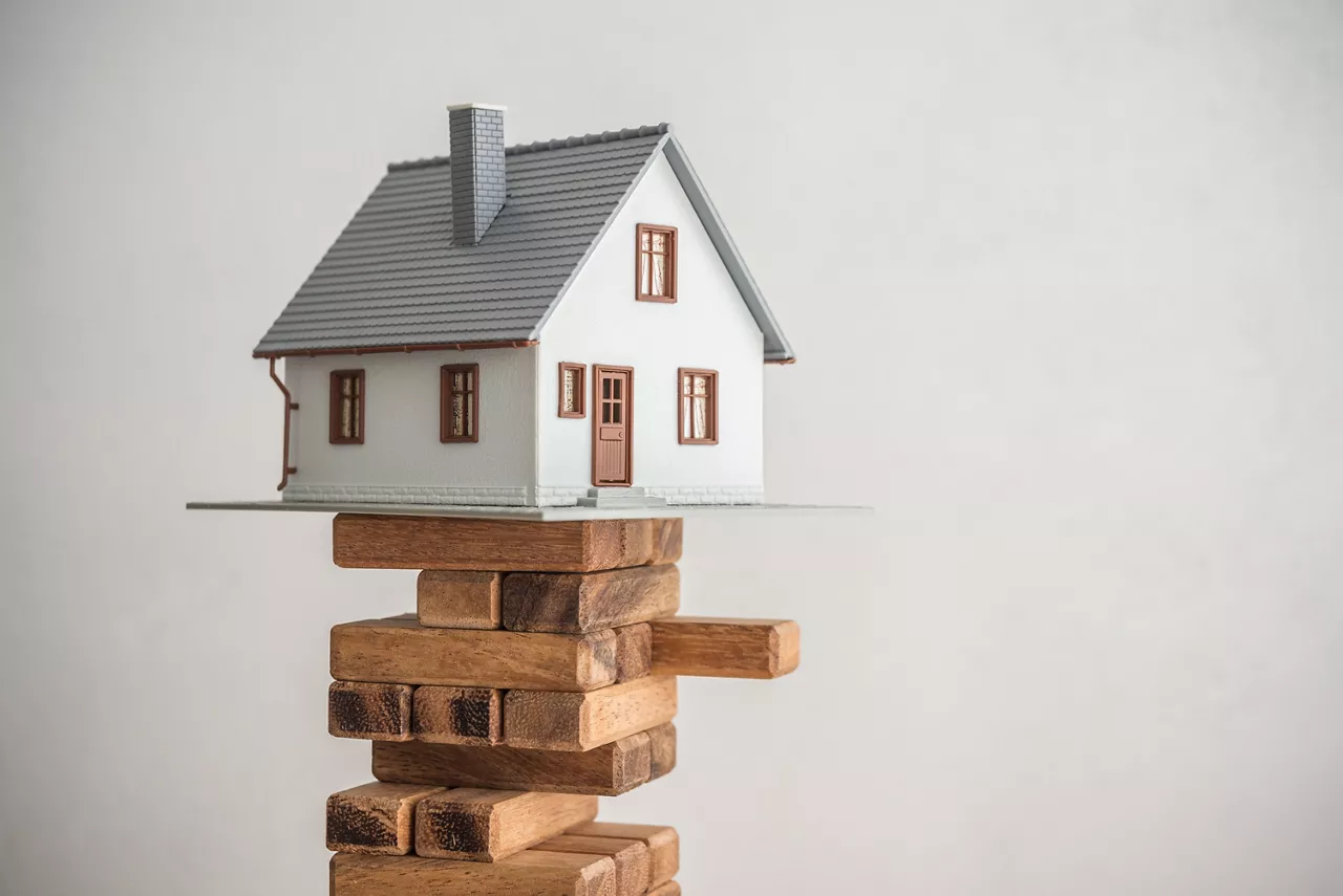 Modern house on wood tower block game white wall background copy space. Mortgage loan for buying home or real estate property, money risk management in financial, foreclosure and bankruptcy  concept.