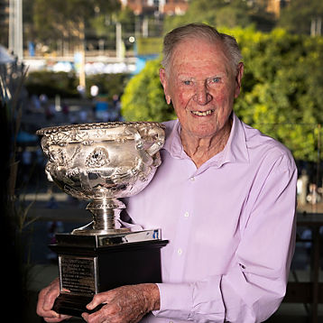 Frank Sedgman poses with a tennis trophy