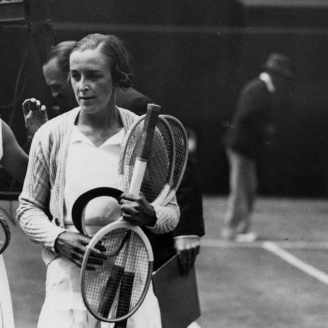 Joan Hartigan carrying her tennis equipment