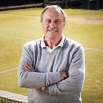 John Newcombe smiles on a grass tennis court