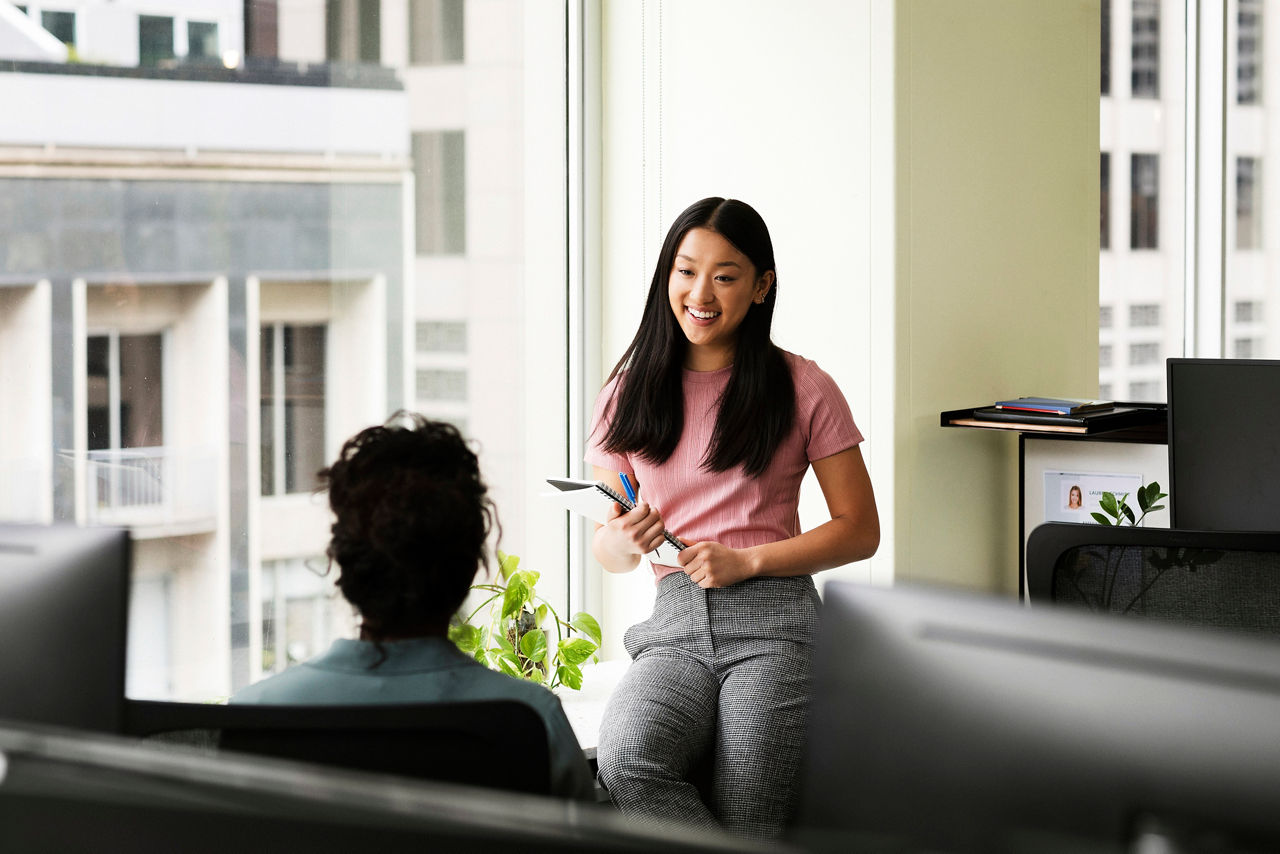 Young women at office window talking to colleague