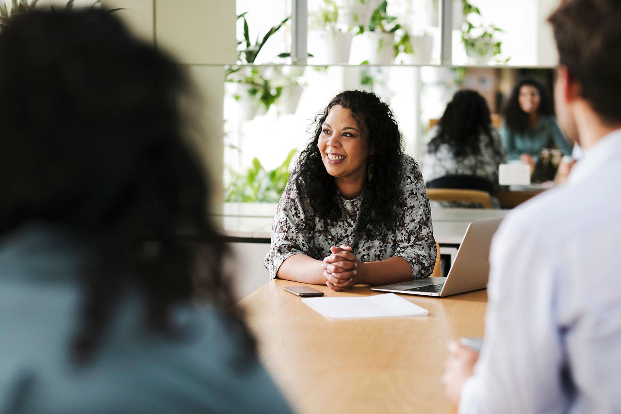 Woman at meeting table with laptop and colleagues