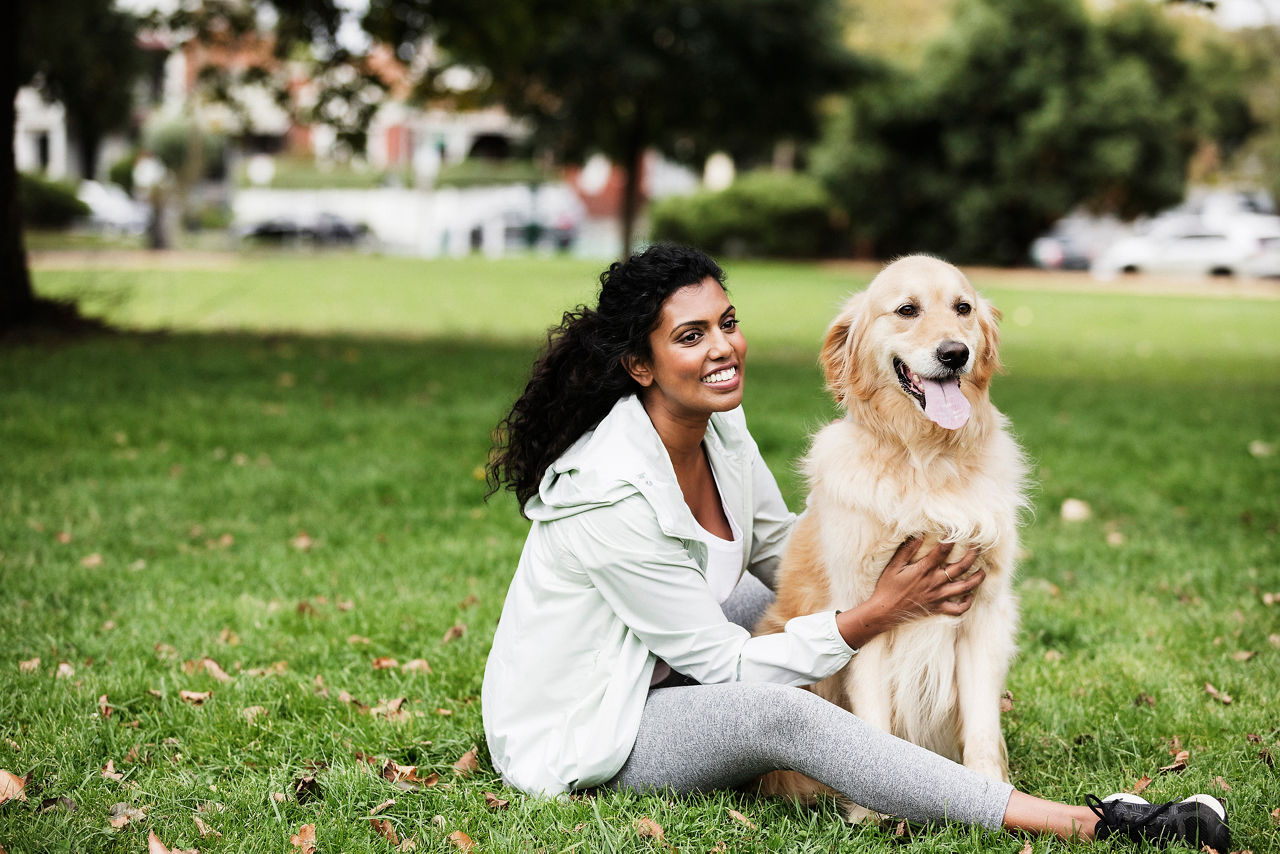 Woman in the park sitting on grass with dog