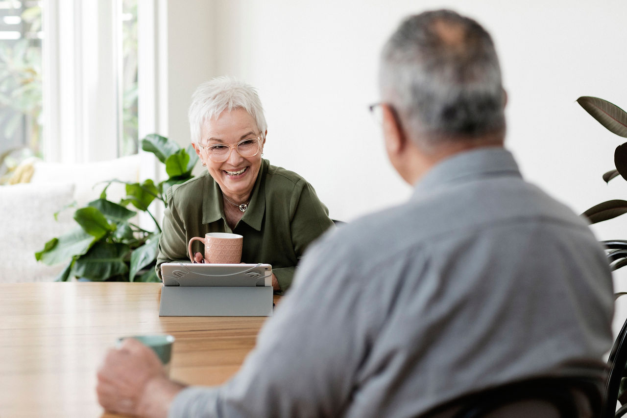 Senior woman smiling at man across kitchen table