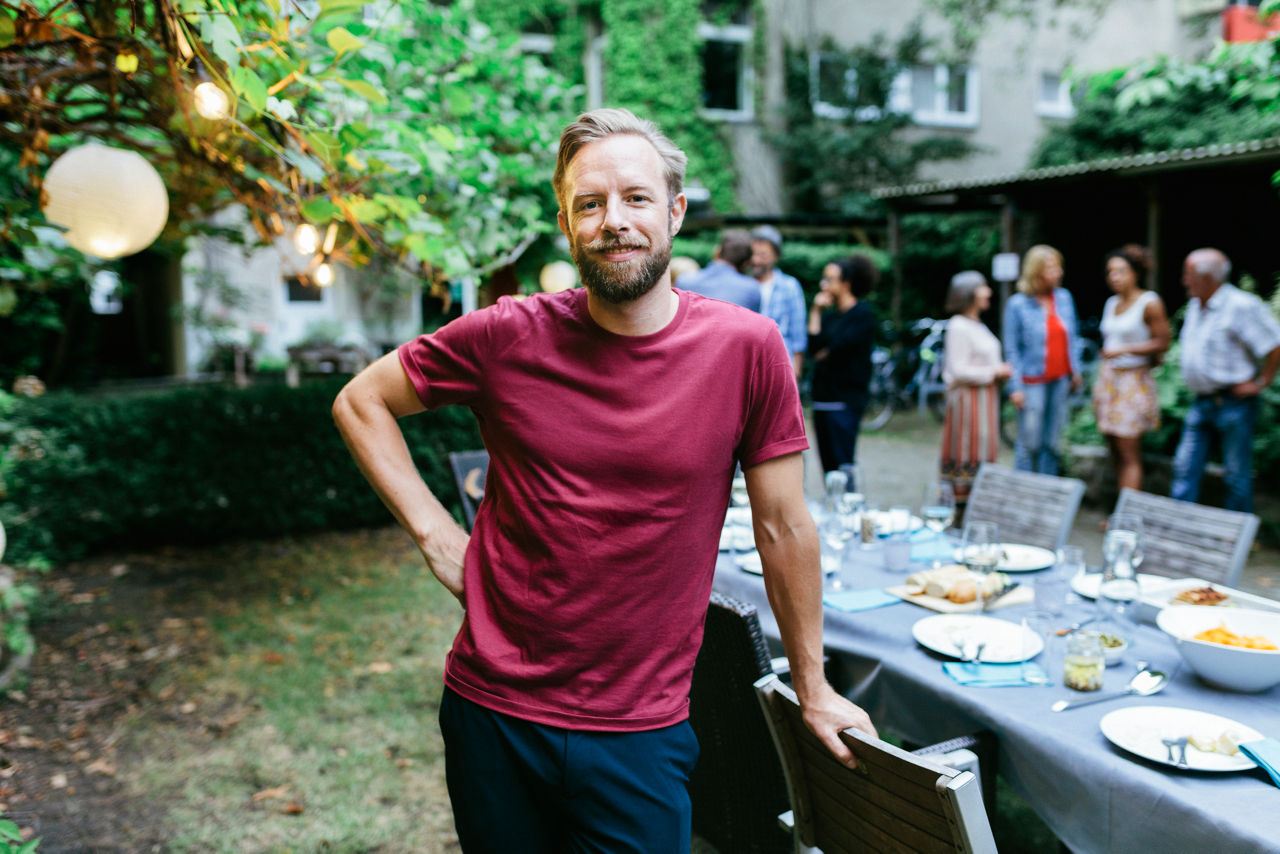 A portrait of a young man smiling after enjoying a family meal outdoors in a courtyard.