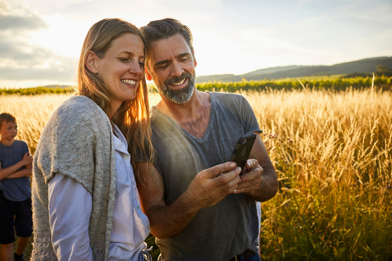 Man showing cell phone to woman in rural landscape