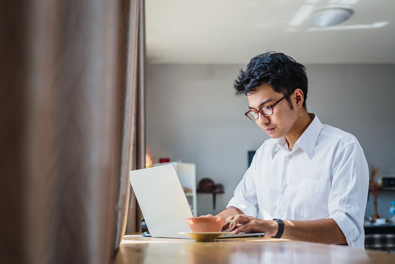 Young Asian business man working with laptop computer while sitting in coffee shop cafe