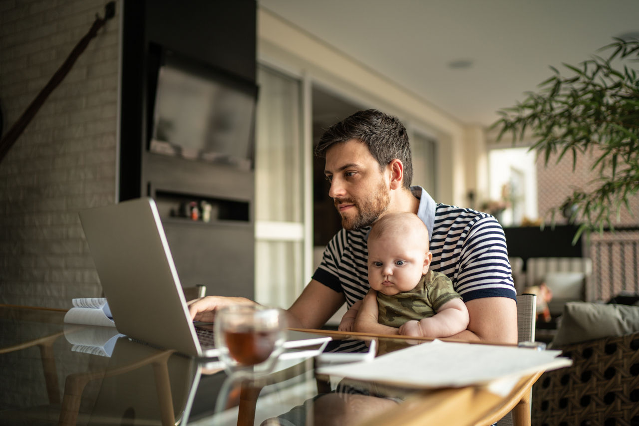Man holding his son and working with laptop at home