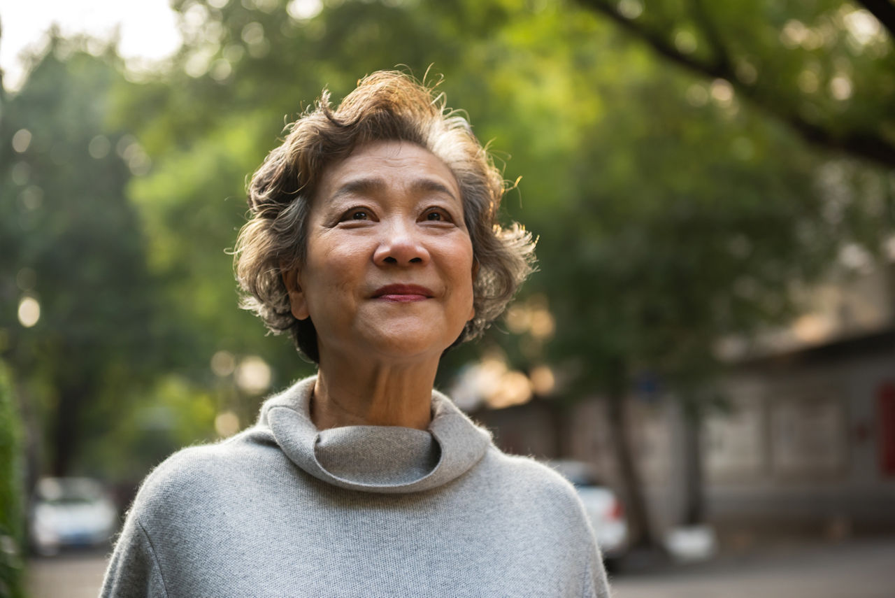 Happy senior woman sitting outside and smiling. Happy senior woman standings outdoors.