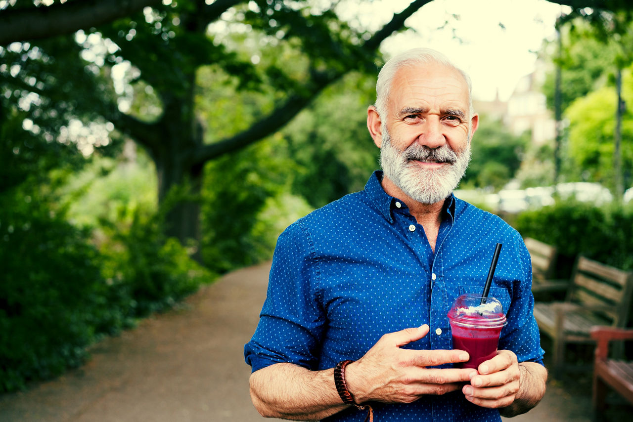 Older man holding a juice drink