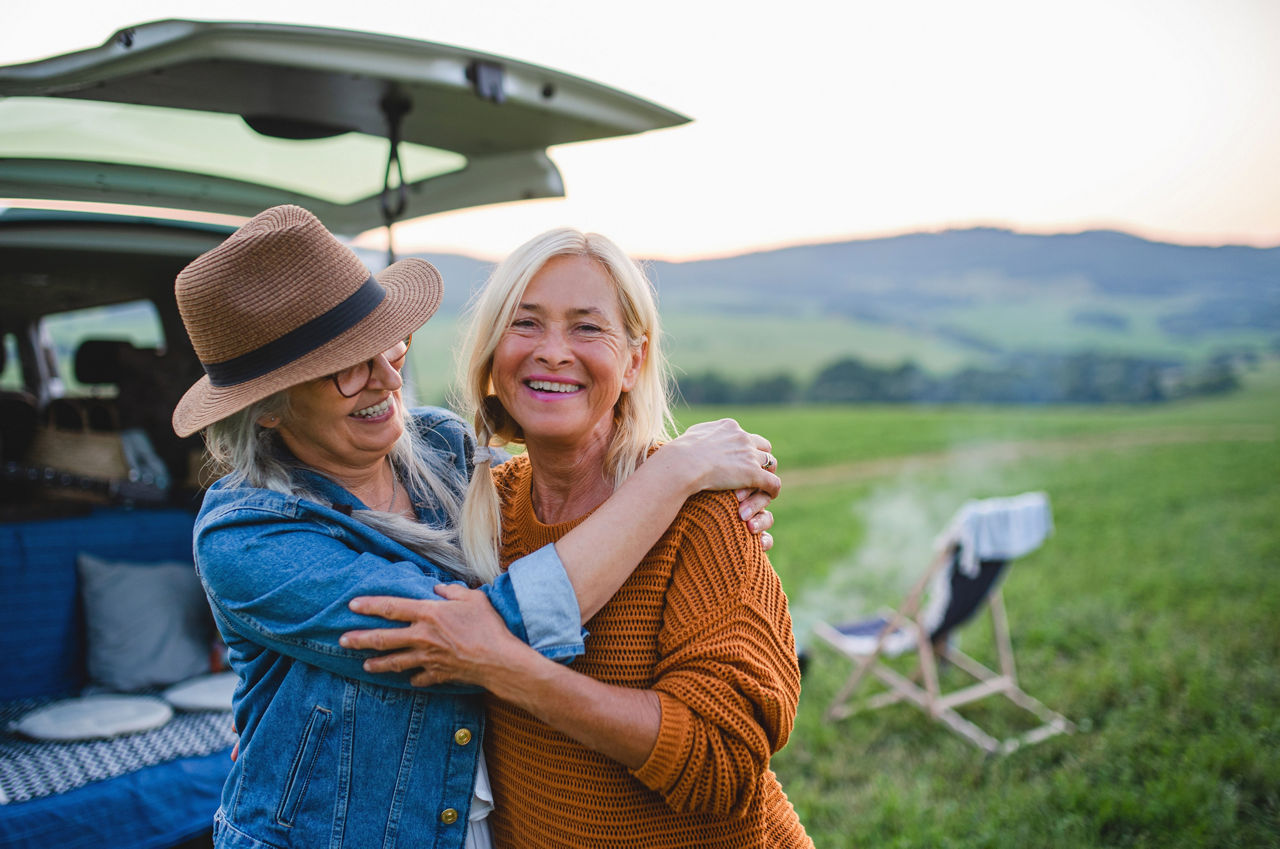 Old women standing by car, hugging.