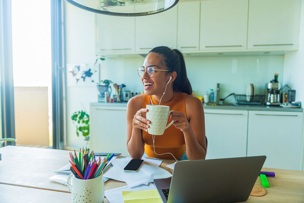 A portrait of a young woman drinks coffee with a laptop in front of her waiting for a video call