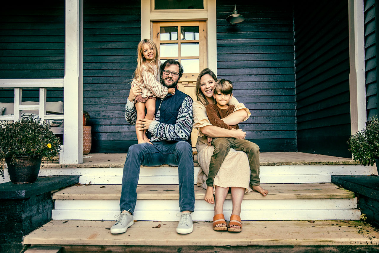 Portrait of young family in front of farmhouse