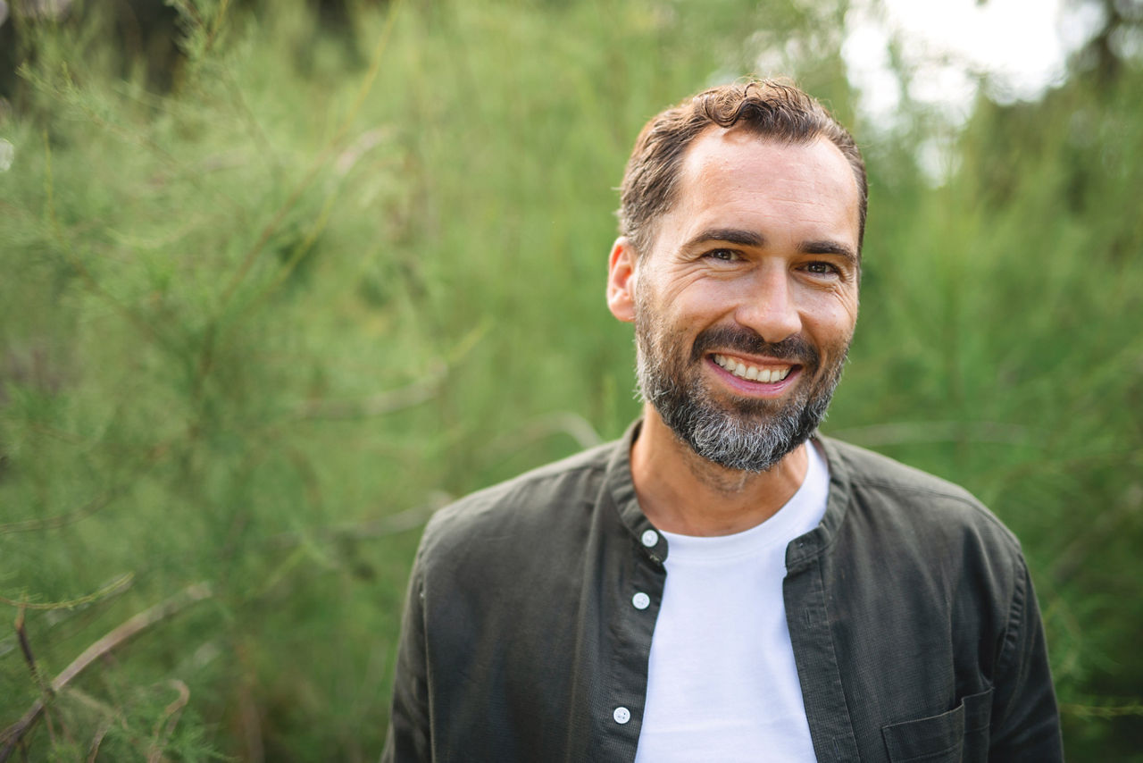 Portrait of handsome mature man smiling and looking at camera outdoors in nature.